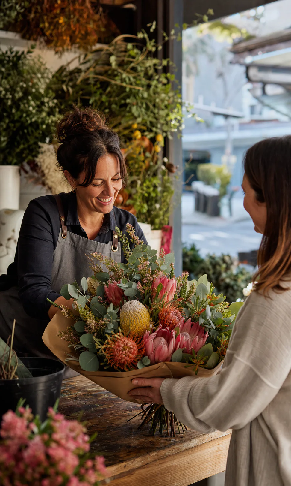 A florist handing a native Australian flower bouquet to a customer